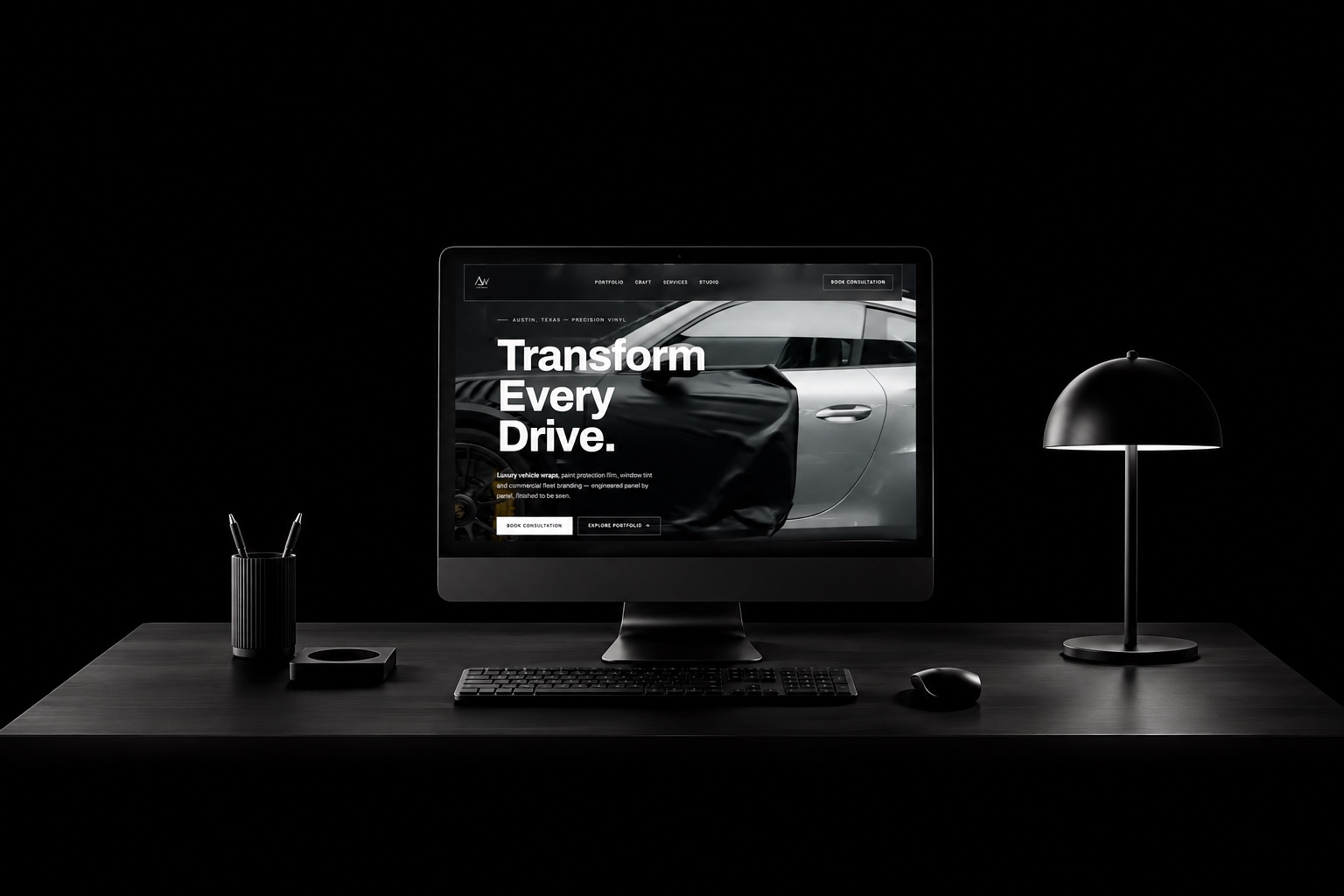 A studio desk in the dark, a monitor showing a vehicle wrap website we designed.